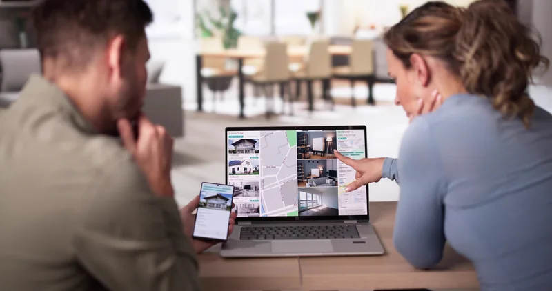 A couple searching home listings on a laptop while house hunting