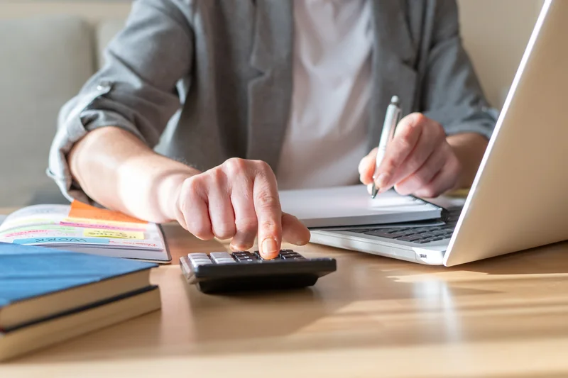A homebuyer reviewing budget figures with a calculator, notes, and a house keychain