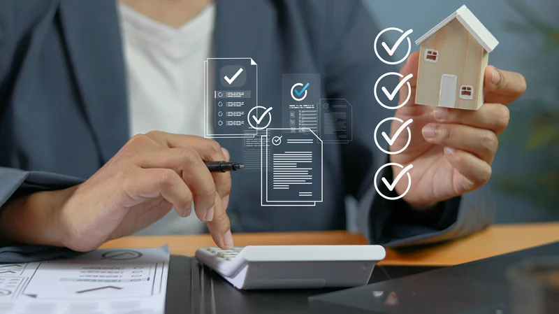 A homebuyer with a calculator and a model house reviewing a checklist of documents for buying a home